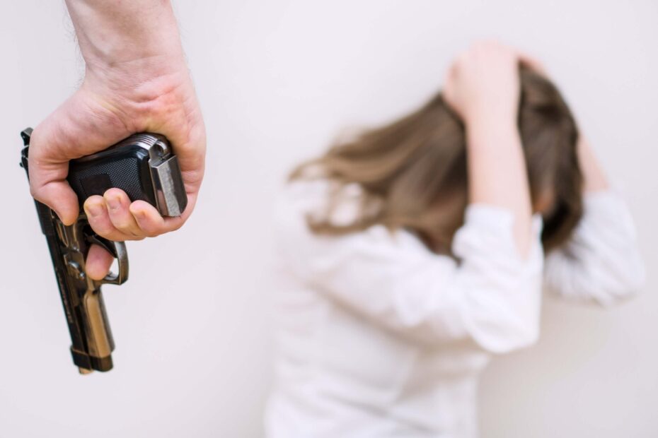 Being shot in a dream | A woman in a white shirt cowers from a man holding a gun.