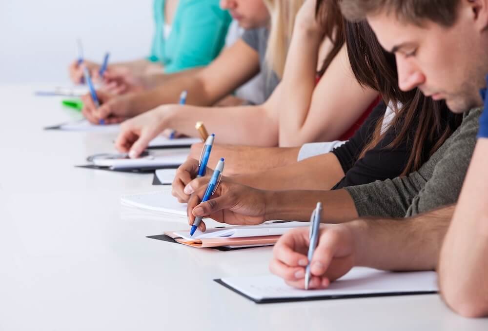 Students sitting in a row, writing.